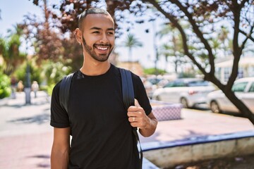 Fototapeta premium Young african american man smiling confident wearing backpack at park