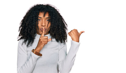 Young african american girl wearing casual clothes asking to be quiet with finger on lips pointing...