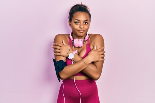 Young african american girl wearing gym clothes and using headphones shaking and freezing for winter cold with sad and shock expression on face
