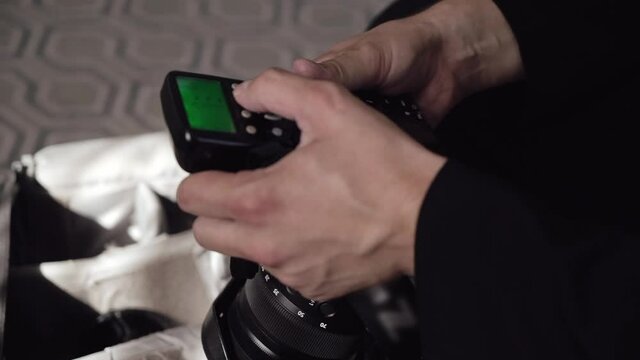 A professional photographer adjusts the flash synchronizer on an SLR camera.