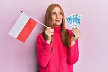 Young irish woman holding poland flag and zloty banknotes smiling looking to the side and staring away thinking.