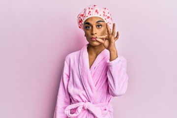 Hispanic man wearing make up wearing shower towel cap and bathrobe mouth and lips shut as zip with fingers. secret and silent, taboo talking