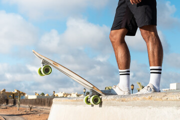 Skater legs at the top of the half pipe. Unrecognizable young skater at the skate park wearing summer clothes © 1 MEDIA