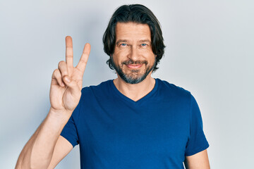 Fototapeta premium Middle age caucasian man wearing casual clothes smiling with happy face winking at the camera doing victory sign. number two.