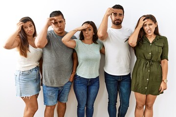 Group of young hispanic friends standing together over isolated background worried and stressed about a problem with hand on forehead, nervous and anxious for crisis