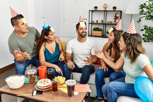 Group of young hispanic friends having birthday party playing funny game at home.