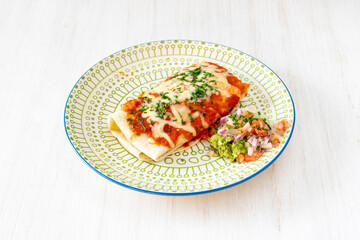 Mexican beef chimichanga wrapped in a wheat tortilla with tomato and cheese, guacamole and pico de gallo