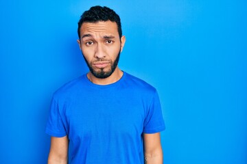 Hispanic man with beard wearing casual blue t shirt depressed and worry for distress, crying angry and afraid. sad expression.