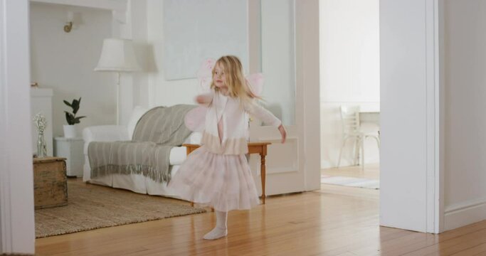 happy little girl dancing playfully pretending to be ballerina funny child having fun playing dress up wearing fairy wings ballet costume at home 4k