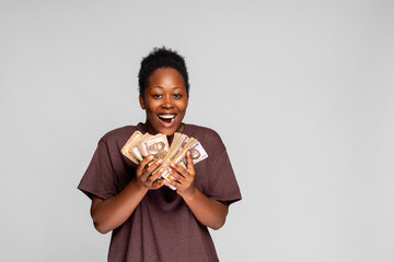 excited and happy young african woman holding a lot of cash