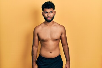 Arab man with beard wearing swimwear shirtless skeptic and nervous, frowning upset because of problem. negative person.