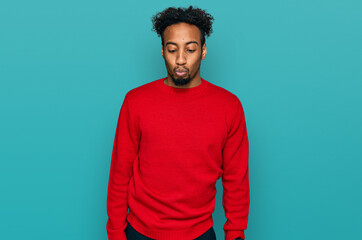 Fototapeta premium Young african american man with beard wearing casual winter sweater making fish face with lips, crazy and comical gesture. funny expression.