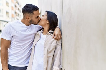 Young latin couple kissing and hugging standing at the city.