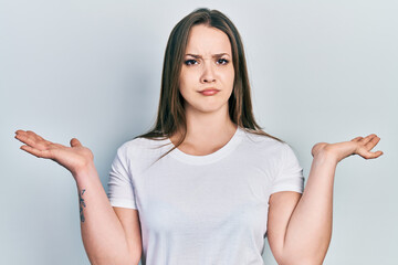Young hispanic girl wearing casual white t shirt clueless and confused with open arms, no idea and doubtful face.