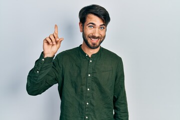 Young hispanic man wearing casual clothes smiling with an idea or question pointing finger up with happy face, number one