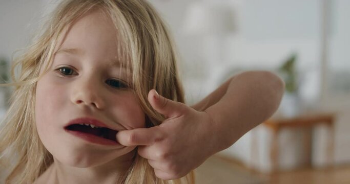 portrait funny little girl making silly faces looking at camera happy kid playfully enjoying childhood having fun at home 4k