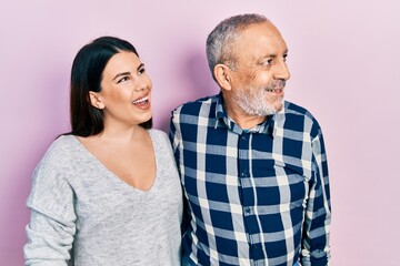 Hispanic father and daughter wearing casual clothes looking away to side with smile on face, natural expression. laughing confident.