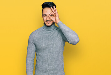 Young arab man wearing casual clothes doing ok gesture with hand smiling, eye looking through fingers with happy face.