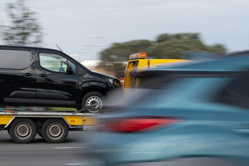 Tow truck transporting car on street. Car service, help on road concept. Motion blur