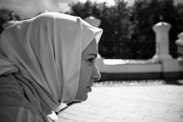 A woman in a headscarf sits with a sad face
