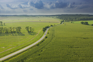 Fototapeta na wymiar Asfaltowa droga przebiegająca przez pola uprawne. Widok z drona.