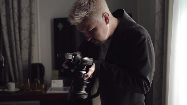 Male photographer takes photographs on a professional camera with flash.