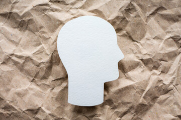 Head symbol on crumpled paper background, mental health and psychology idea