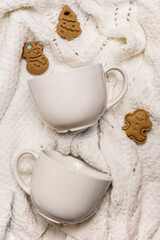 Gourmet white cups with christmas cookies. White knitted sweater background. Mockup for the new year. Christmas concept. Perfect for presentations, decor and web design.