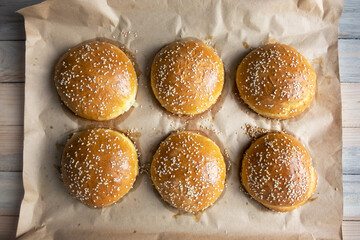 Homemade burger bun on bakery parchment on wooden table. Food photography