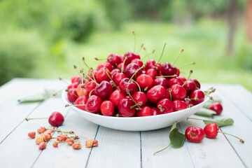 Cherry (merry) berry heap with leaves on wooden table in garden closep. Food photography