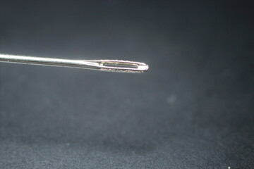 Small needle with empty eyelet, isolated over the black background.