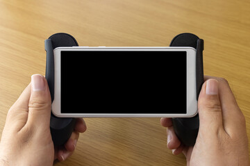 ゲーム用グリップスタンドを取り付けたスマートフォンを持つ男の手