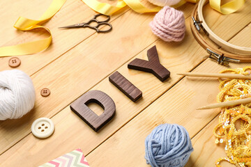 Composition with word DIY and knitting supplies on wooden background