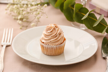 Plate with tasty wedding cupcake on table