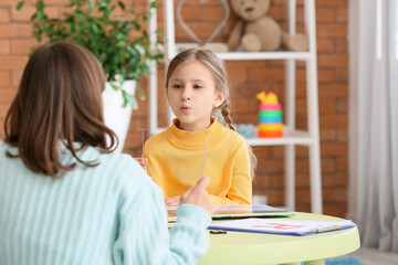 Speech therapist working with cute girl in clinic
