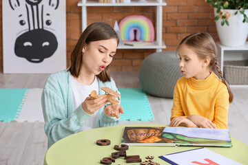 Speech therapist working with cute girl in clinic