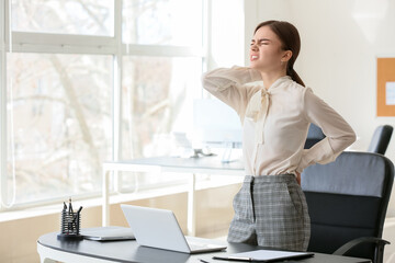 Young businesswoman suffering from back pain in office