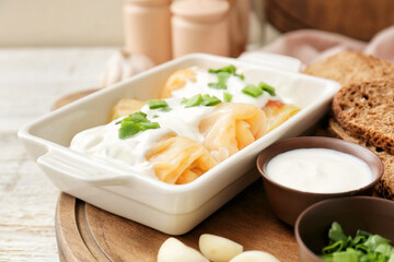Baking dish with tasty stuffed cabbage rolls and sauce on table