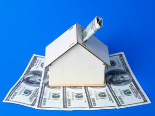 Miniature home with dollars. Cost of maintenance or buying house. Property lending and loan cost.