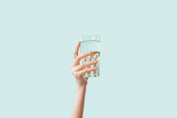Female hand with glass of water on color background