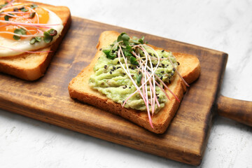Wooden board with tasty toasts on light background, closeup