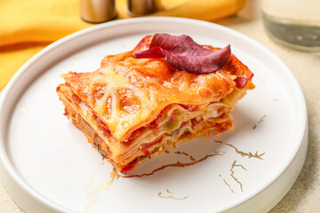 Delicious lasagna with tomato sauce in plate on table, closeup