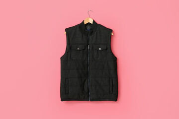 Hanger with vest jacket on color background