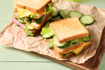 Board with tasty sandwiches on color wooden background, closeup