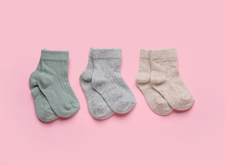 Different baby socks on color background