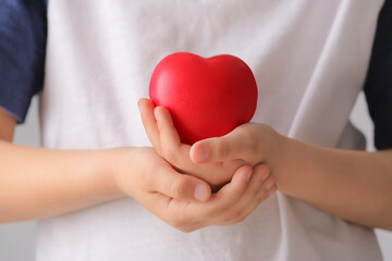 Child holding red heart, closeup. Cardiology concept