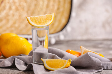 Shot of tasty tequila with lemon on table, closeup