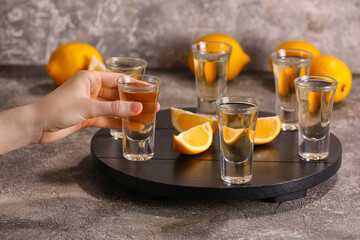 Woman with shot of tasty tequila and lemon on grunge background