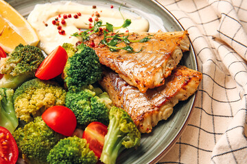 Plate with tasty baked cod fillet and vegetables on table, closeup
