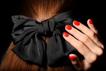 Woman with beautiful manicure and stylish hair bow on dark background